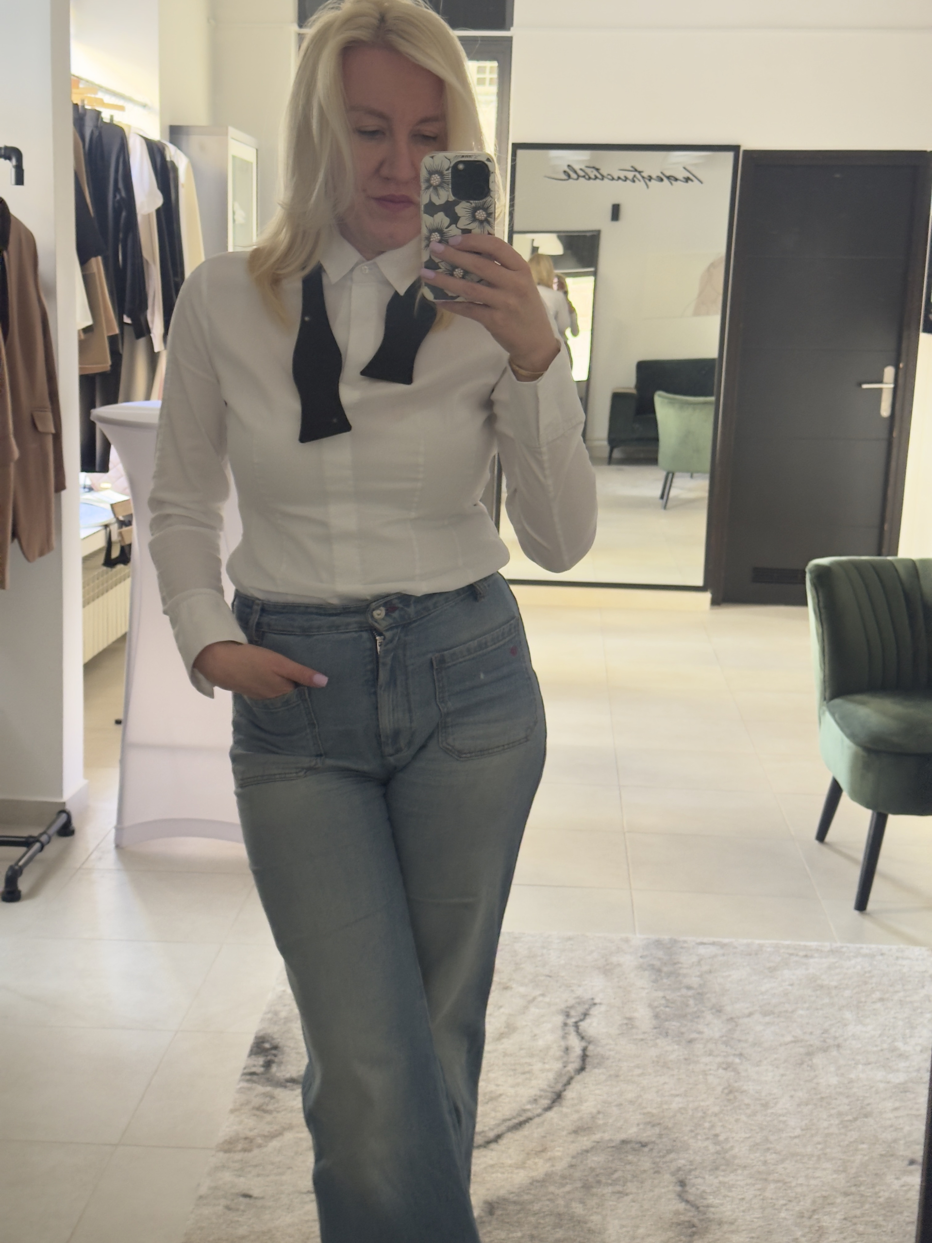 Žena nosi crnu žensku kravatu uz bijelu košulju i traperice - casual elegantan look