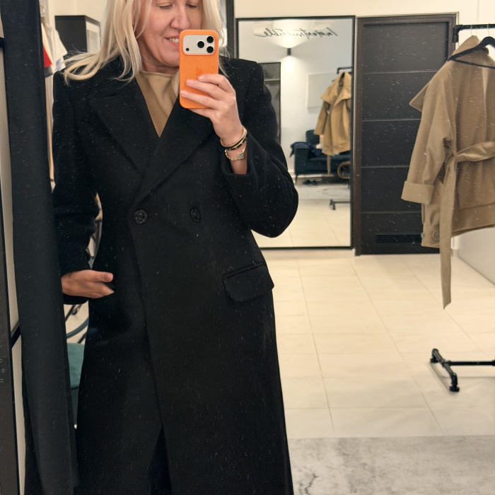 Žena u crnom dugom dvorednom kaputu Alex, selfie u ogledalu u Indestructible concept storeu